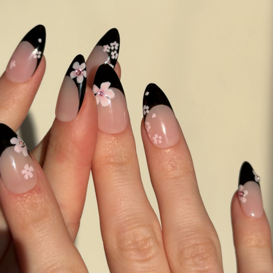 Nails with black and white floral design on a beige background